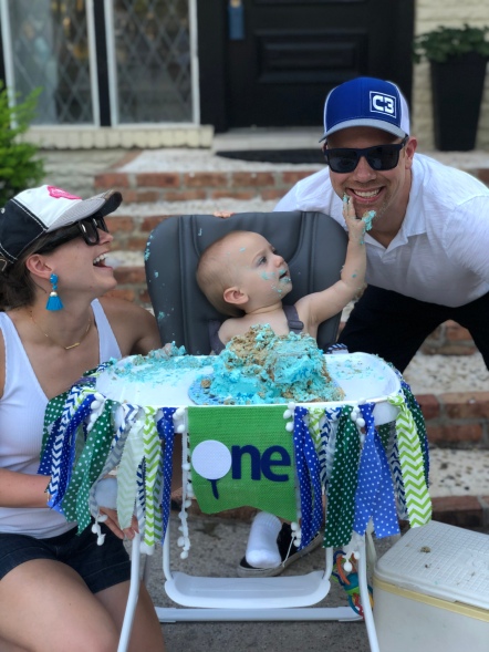 Wes and Nicole with Easton at his first birthday party while Easton puts cake on Wes' face